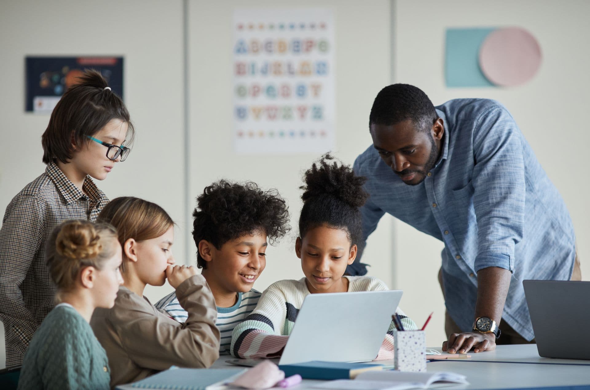 Children at laptops with an adult beside them